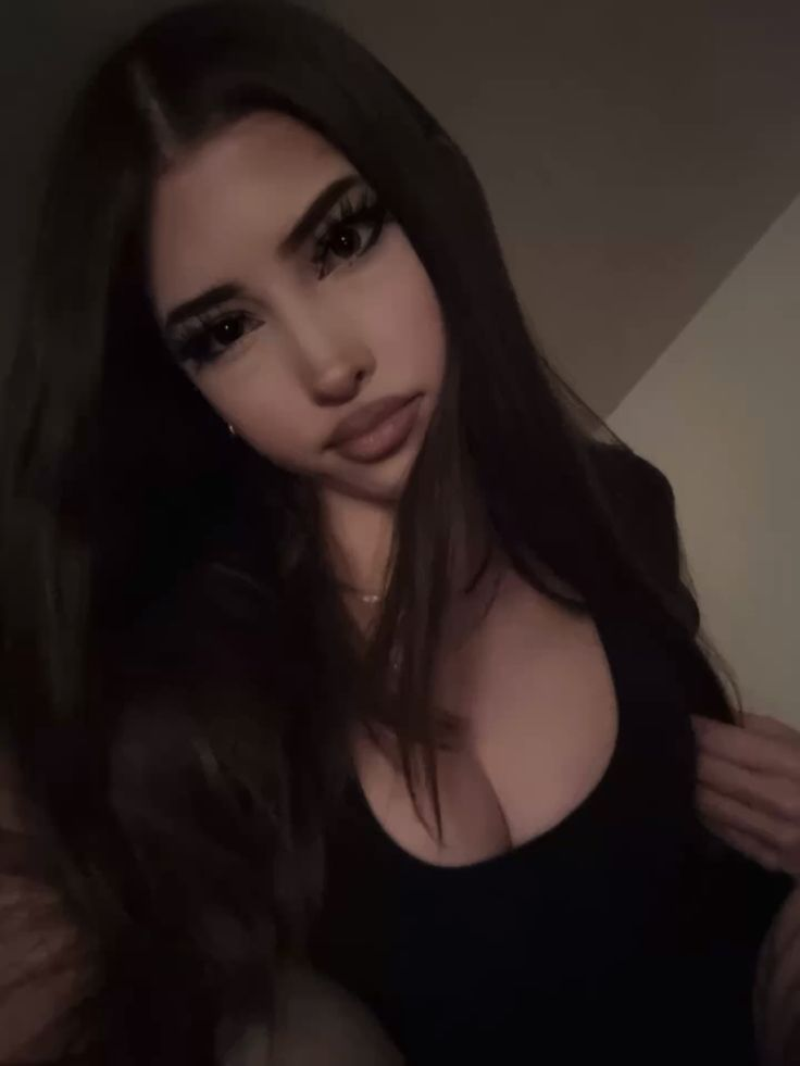 Dimly lit selfie of woman in black top