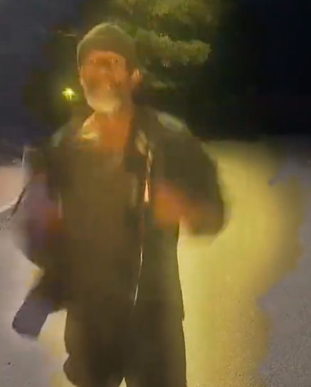 Blurry image of a man in a beanie and jacket, appearing to be moving at night