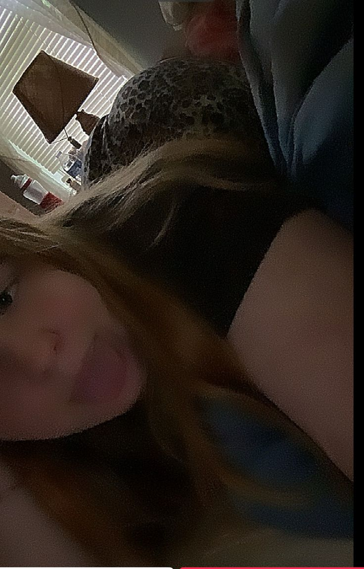 A selfie of a person lying down, sticking their tongue out, with long hair