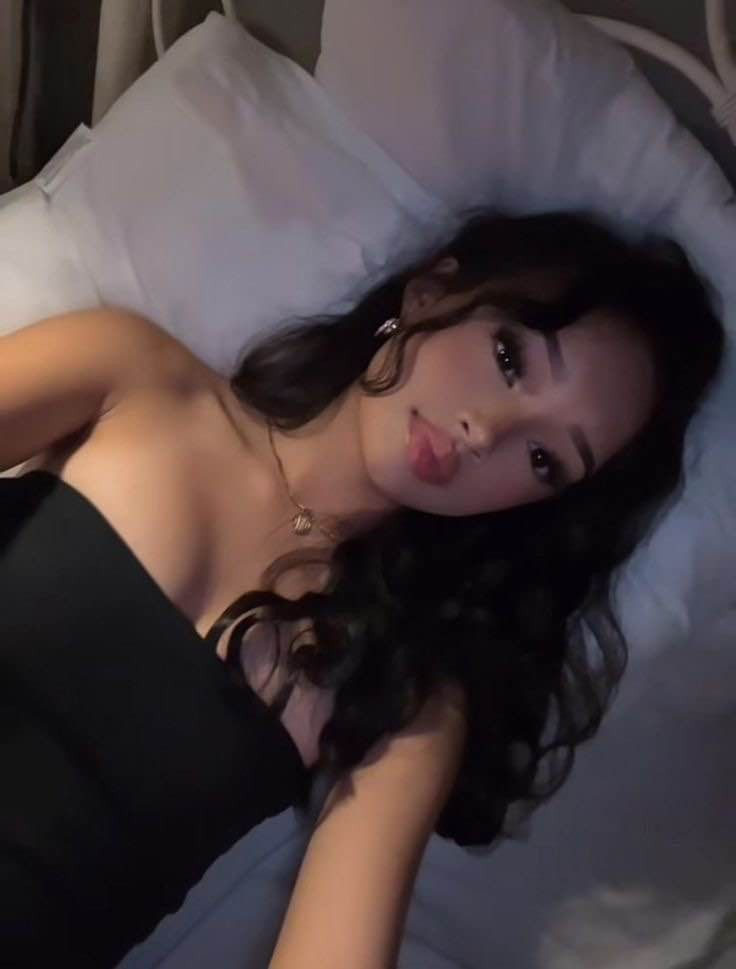 Dimly lit selfie of a woman with dark wavy hair