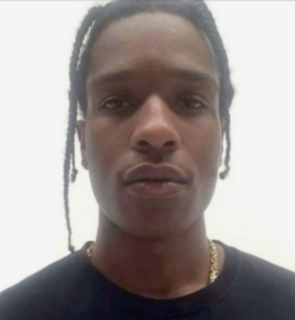 A headshot of A$AP Rocky with braided hair, looking directly at the camera