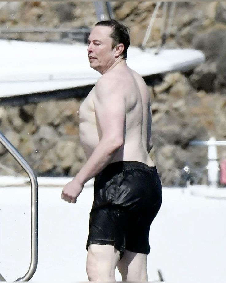 A shirtless man in black swim shorts on a yacht, photographed from the side